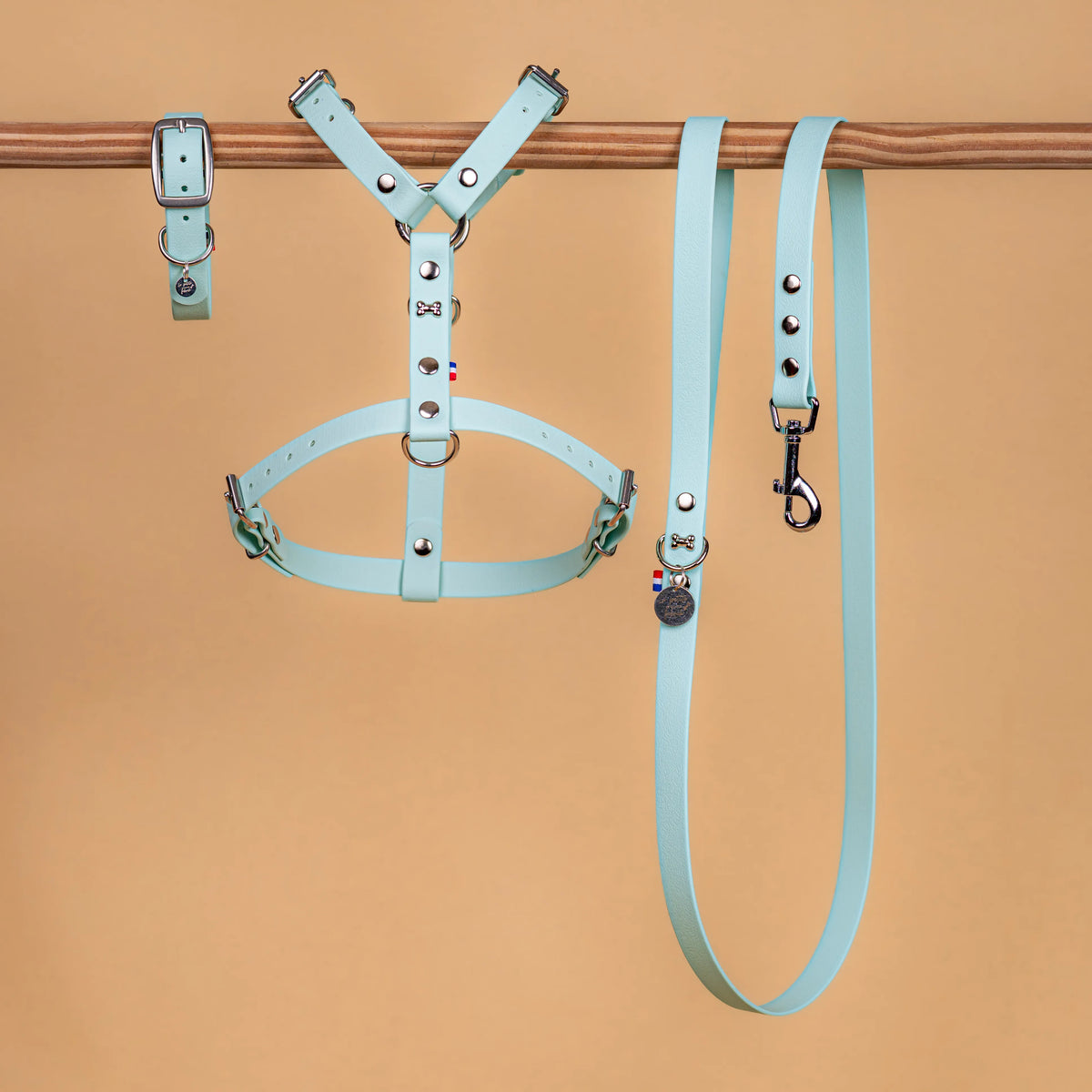 ensemble collier harnais et laisse vendu séparément en sangle enduite similaire au biothane présenté cote a cote sur une barre couleur bleu pastel