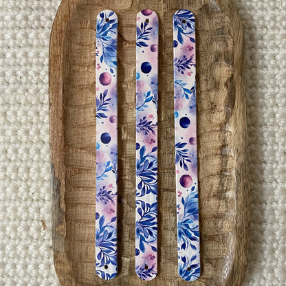 Vue de dessus à plat de trois bandes en biothane pour collier de chien, illustrées d'un motif interchangeable chien artistique aux feuilles bleues et touches d'aquarelle mauves sur fond clair.
