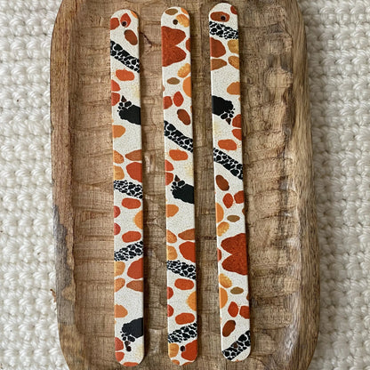 Vue de dessus à plat de trois bandes en biothane pour collier de chien, décorées d'un motif interchangeable chien animalier aux taches terracotta, orange et détails noirs sur fond neutre.