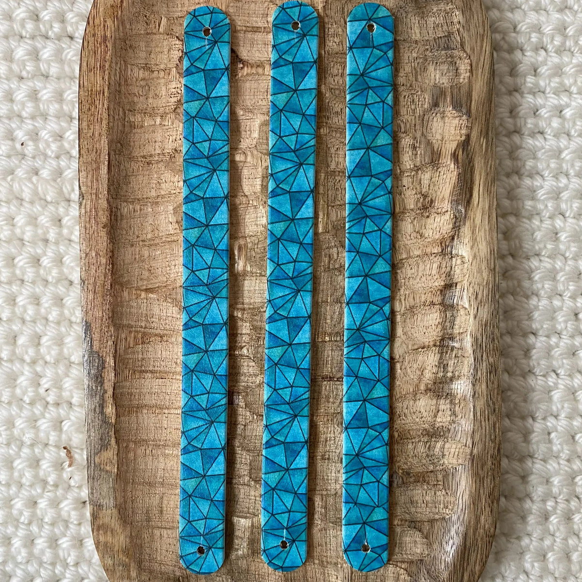 Vue de dessus à plat de trois bandes en biothane imprimées pour collier de chien, avec un motif interchangeable chien de pavage géométrique polygonal bleu cyan et turquoise.