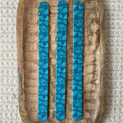 Vue de dessus à plat de trois bandes en biothane imprimées pour collier de chien, avec un motif interchangeable chien de pavage géométrique polygonal bleu cyan et turquoise.