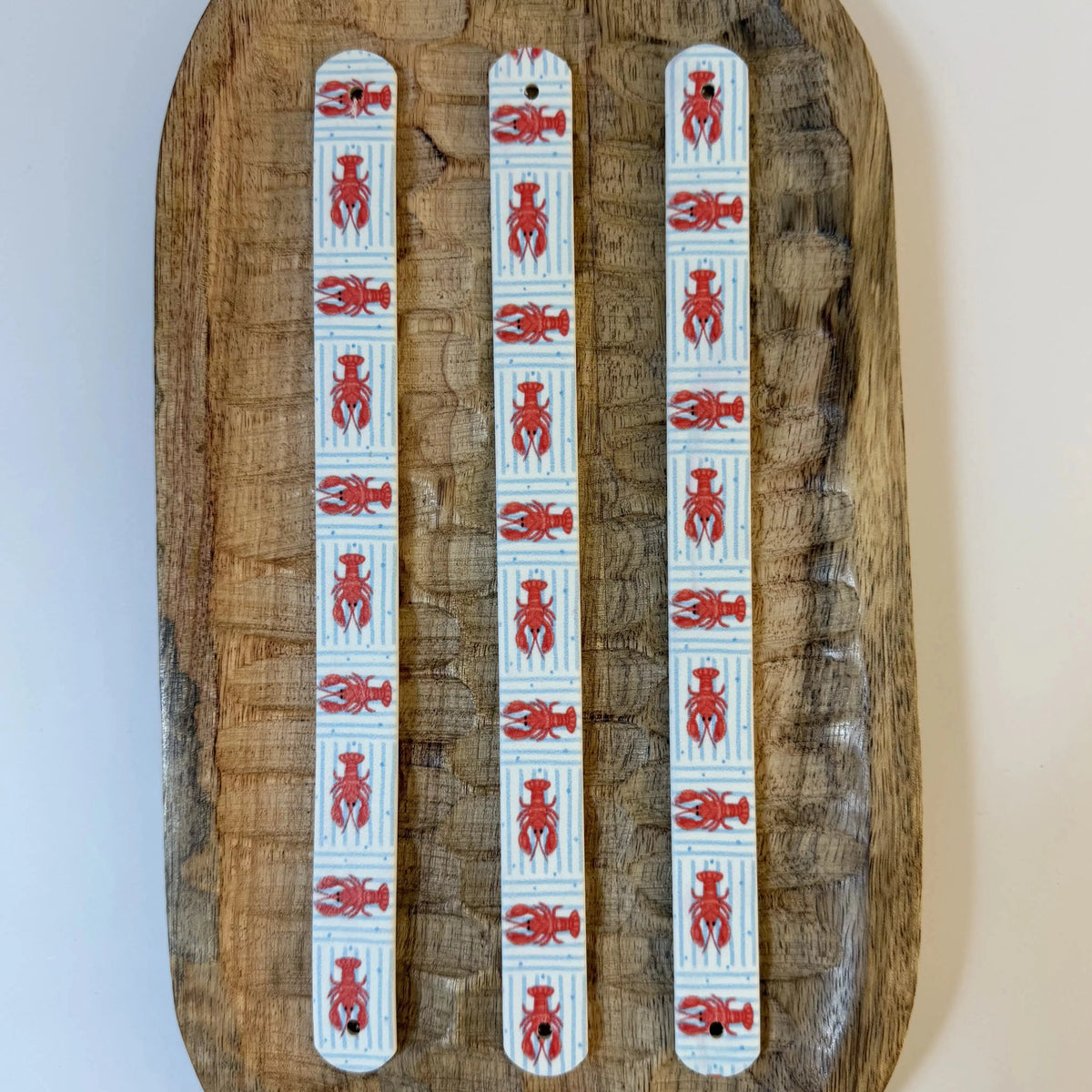 Trois bandes en biothane avec motif interchangeable chien marinière à rayures bleues et petits homards rouges.