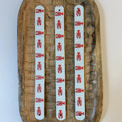 Trois bandes en biothane avec motif interchangeable chien marinière à rayures bleues et petits homards rouges.