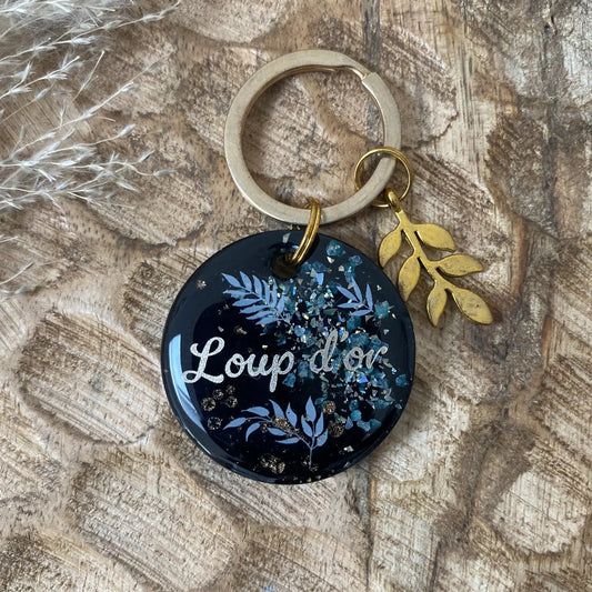 Détail des motifs botaniques bleus et des reflets pailletés sur résine noire