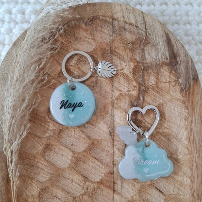 Médaille personnalisée pour chien en résine aux tons doux bleu ciel et argent posée sur un support en bois