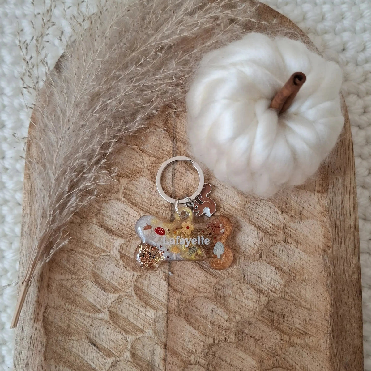 Médaille ronde personnalisable pour chien modèle Automne Enchanté posée sur une surface en bois texturé sculpté